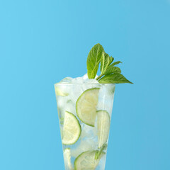 Glass of mojito cocktail on blue background closeup