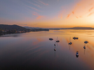Naklejka premium Sunrise over the water with fog, boats, clouds and reflections