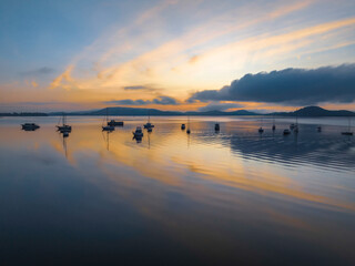 Sunrise over the water with fog, boats, clouds and reflections