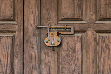 Old rusty iron lock securing a rustic wood door