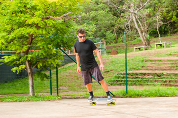 pequenas manobras em cima de uma chapa de skate do modelo homem com óculos escuro 