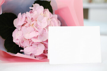 Blank white gift card on the background of a bouquet of flowers