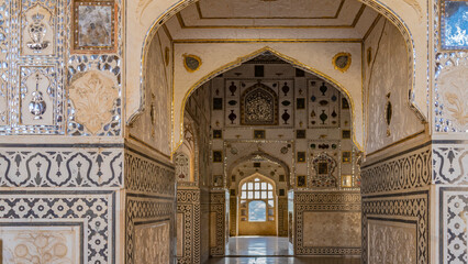 The interior of the famous mirror palace in the ancient Amber Fort. Arched openings, a barred...