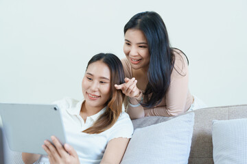 lgbtq, lgbt concept, homosexuality, portrait of two asian women posing happy together and loving each other while playing tablet at sofa