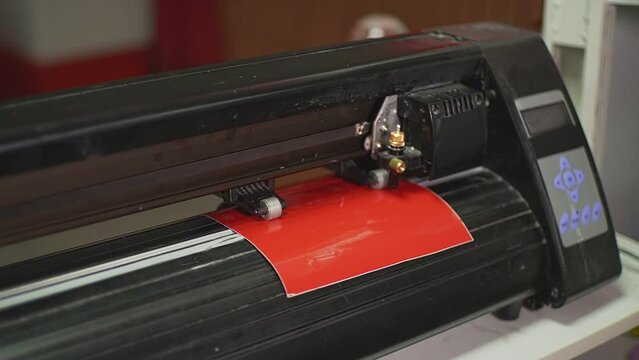 a cutting plotter cuts out a pattern on a red film. High-quality Full HD video recording. slow motion video
