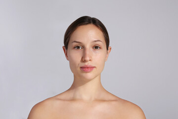 Studio portrait of young beautiful woman with long black hair tied in ponytail and clean face skin....