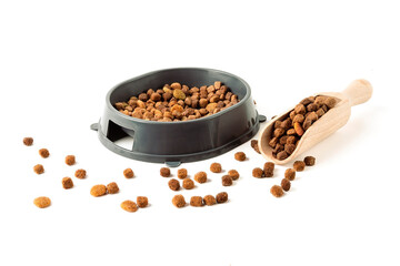 A bowl of dry pet food and a scoop for dry food on a white background.