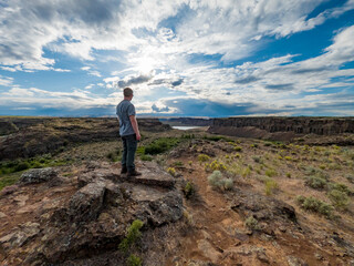 Athletic adventurous male hiker standing on a ridge looking down into a valley along the Columbia River.

