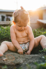 Portrait of adorable baby girl playing in the garden, getting dirty while exploring and learning...