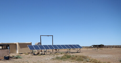 Geese sheltering on the shade cast by solar panel;s used for rewable energy on a farm in Bushmanland, South Africa