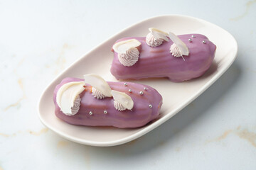 Two eclair cakes with violet frosting on white plate