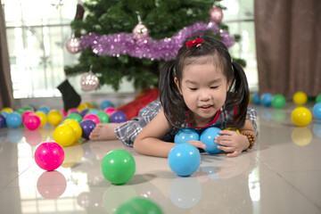 Fototapeta na wymiar little Asian girl with colorful balls in front of a Christmas tree