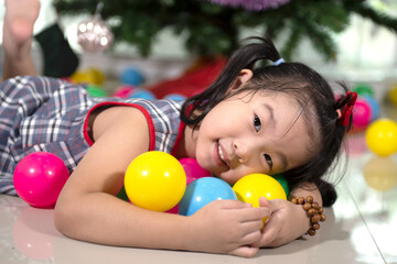 Fototapeta na wymiar little Asian girl with colorful balls in front of a Christmas tree