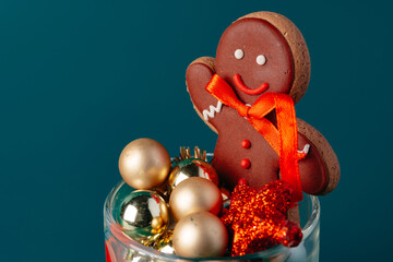 Glass with Christmas decorations on dark green background