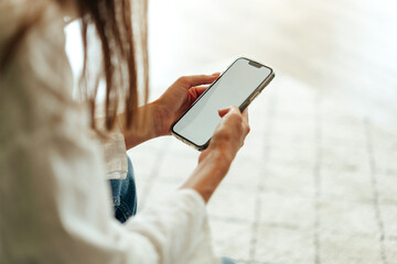 Young woman sitting on the couch and using her smartphone