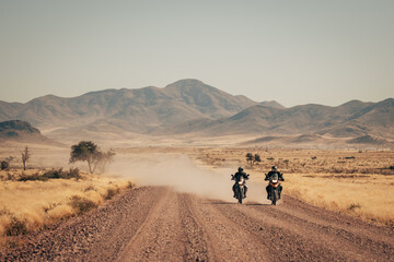 Panorama - Zwei Motorradfahrer fahren entlang einer einsamen Straße, Naukluft Gebirge, Namibia - obrazy, fototapety, plakaty