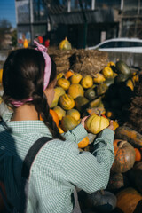 Woman with a small pumpkin among the autumn harvest