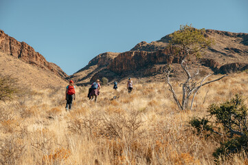 Familie wandert in der Morgensonne über den Olive Trail, einen Pfad im Naukluft Gebirge, Namibia