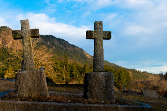 An image of two old weathered stone crosses in a historic cemetery. 