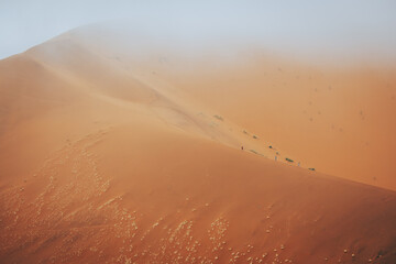 Drei Kinder laufen über einen Grat der in Nebel getauchten Düne Big Daddy im Sossusvlei (Namibia)