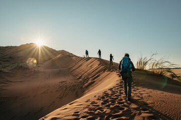 Fototapeta na wymiar Foto im Gegenlicht - Touristen besteigen die Elim Düne bei Sonnenuntergang (Sesriem, Namibia)