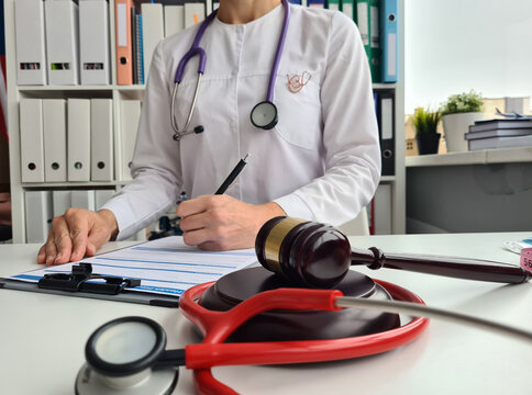 Doctor fills out legal document in office at table