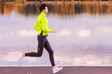 Handsome Fitness Runner Man During Road Training for High Intensity Interval Training and Sprint Workout Outdoors At Fall Near Scenic River Bank As Male Athlete Model Fit