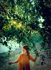 A lot of tree leaves with a girl walking in the summer park near lake with sun glowing through branches