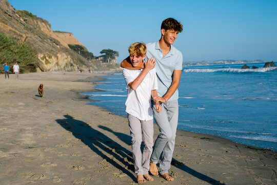 Brothers Walk At Beach While Older Brother Playfully Grabs Sibling