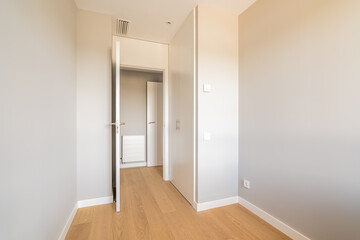 Fototapeta na wymiar Empty room with laminate flooring and door leading to corridor. Repair and construction concept.