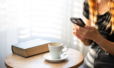 Young Asian woman's hand using smartphone while sitting in a cafe