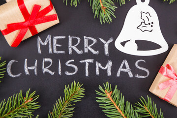Decoration for Christmas. Inscription Merry Christmas, wrapped gifts, bell shape and spruce branches on black background