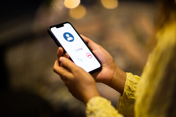 Close up of female hands using mobile smartphone in bright yellow bokeh lights in night city.