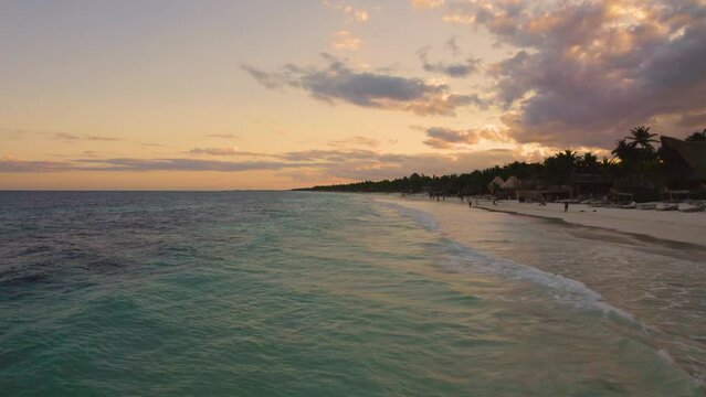 Aerial view close to the the carribean ocean at the Akiin beach in Tulum, Mexico during Sunset with people enjoying their beach holiday.