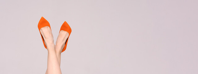 Beautiful female legs with high heels in bright orange color isolated on a light background