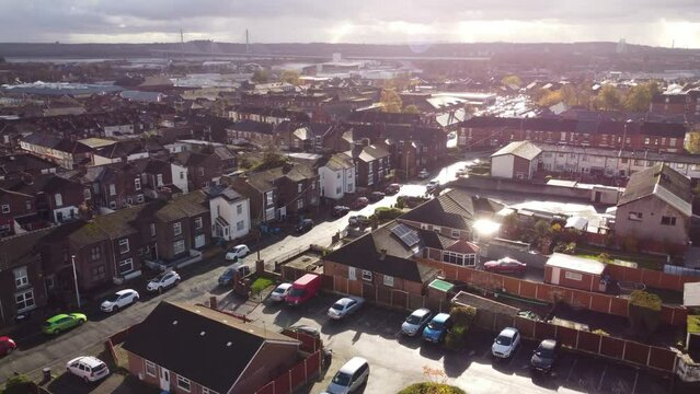 Sunset aerial view rising above suburban Cheshire townhouse property with gateway bridge on horizon