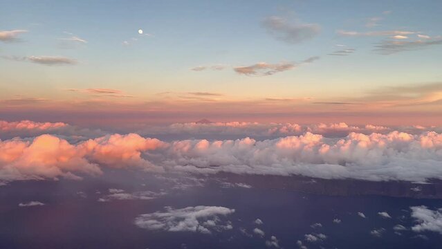 Side view from the cabin of a commercial plane in flight at sunset flying over the clouds