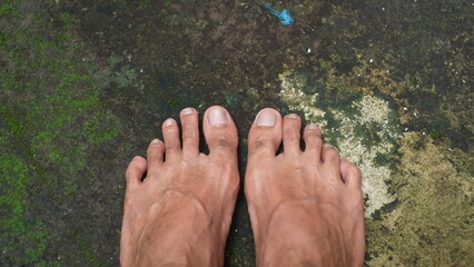 asian man's feet on abstract background, mossy floor, cement texture