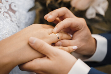the groom puts on the wedding ring to the bride, close-up