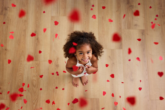 Overhead view of happy young girl surrounded by heart shaped confetti