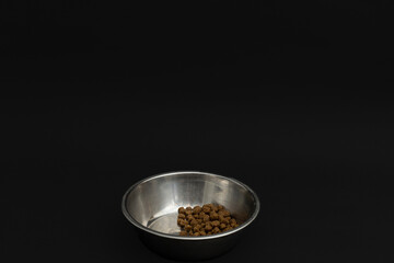Dry dog food in an aluminum plate on a black background, dog food