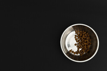 Dry dog food in an aluminum plate on a black background, dog food