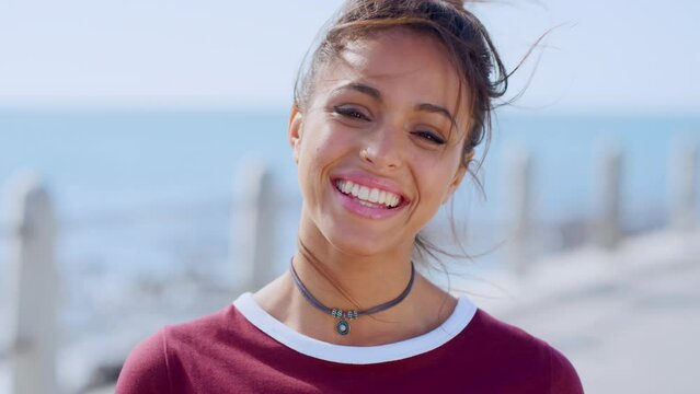 Woman, face or windy hair by beach, ocean or sea in travel location, Portugal summer break or holiday vacation. Portrait, smile or happy student, tourist or fashion person and makeup cosmetics