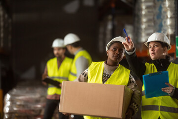 A multiracial group of people is working in a distribution warehouse, the manager is giving instructions to the workers.