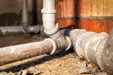 Sewer pipes in home basement. System of gray sanitary pipes when building a house. Sewer...