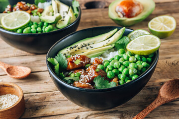 Buddha bowl with crispy sesame chicken asian style. Sweet and sour fried chicken with steamed rice, peas and acocado