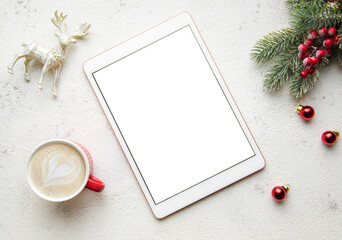 Christmas decorations and tablet on white concrete background.
