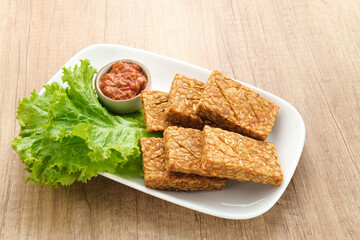 Tempeh, Tempe Goreng or Fried tempeh is Indonesia traditional food, made from fermented soybean seeds. Served with sambal (chilli sauce)
