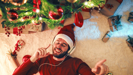 Happy man listening music under the Christmas tree