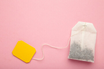 Tea bag with yellow blank label on pink background. Copy space for text.